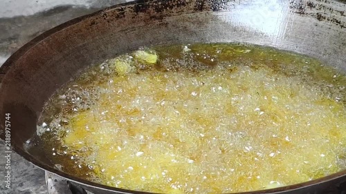 Deep frying food in hot boiling cooking oil inside a traditional metal wok pan
