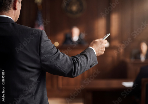 Lawyer standing in a wood paneled courtroom presenting a case before the presiding judge
