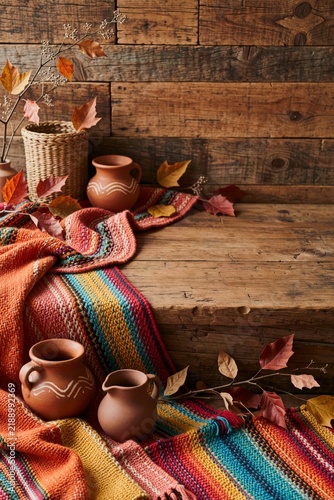 Vibrant woven textiles, terracotta ceramics, natural wood and autumn foliage create a warm Mexican seasonal celebration scene
