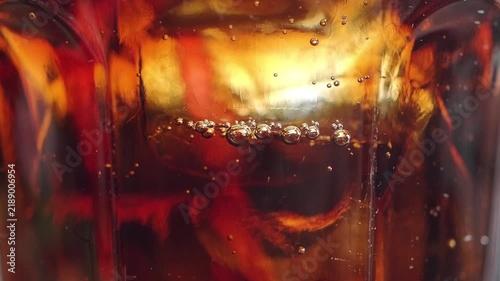 Bubbles rise in a glass of dark beverage captured close up