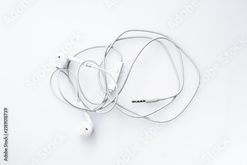 Obraz na plátně Top-down view of messy tangled white wired earphones isolated on a white background representing frustration and disorganized technology