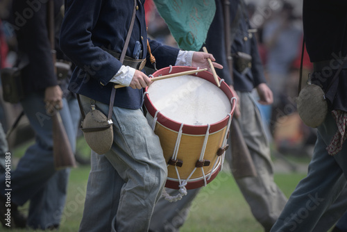 Fotografie A Civil War reenactor portraying a Union Army drummer marches with infantry while carrying a rope-tension field drum and drumsticks