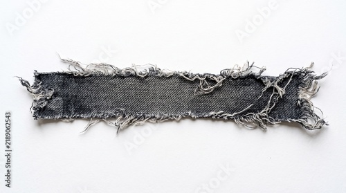 Black denim fabric strip with frayed edges and rough texture