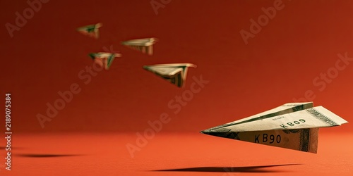 Paper airplanes made from money fly across a warm, textured red background