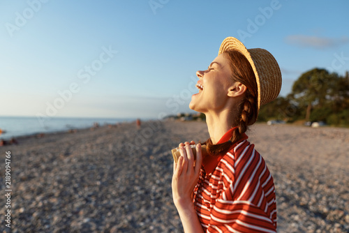 Картината върху платно A happy young woman in a straw hat enjoys the summer lifestyle outdoors on a sandy beach