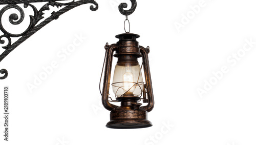 Konstfotografi Antique kerosene lantern hanging from ornate wrought iron bracket, isolated on t