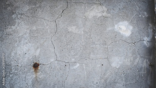 Old weathered concrete wall texture with cracks and a rusty bolt, industrial background