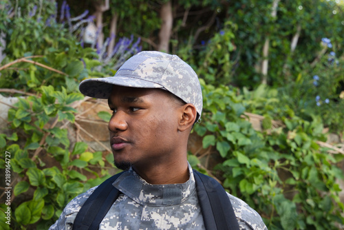 Foto Standing by stone wall, African American man wearing camouflage uniform and back