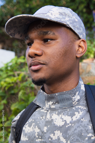 Bild auf Leinwand African American male wearing camo cap jacket carrying pack strap looking left b