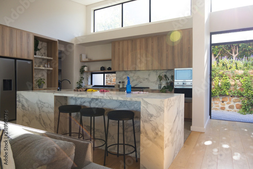 Marble kitchen island is anchoring bright modern kitchen with three black bar stools
