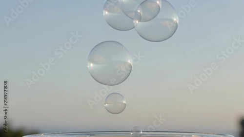 Macro Floating Soap Bubbles Rising from Glass Against Neutral Sky