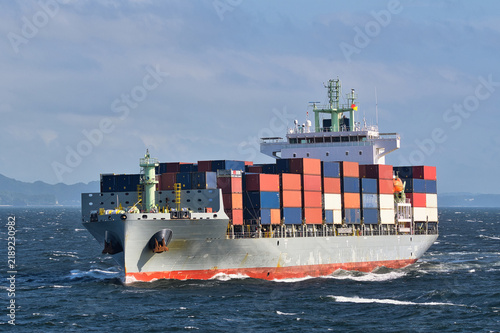Container ship sailing on rough seas with stacked cargo containers