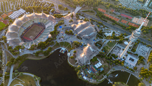 High angle aerial view of Olympiapark Munich with Olympic Stadium and Olympiaturm TV tower at golden hour sunset. 