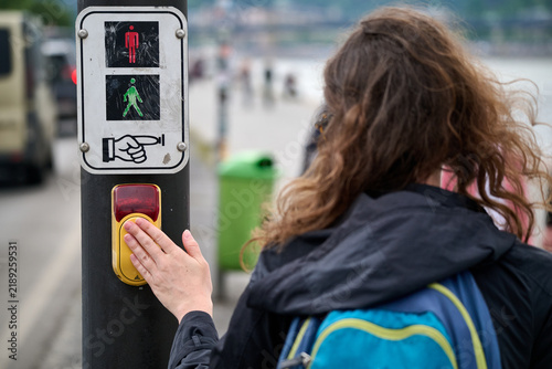Cuadro en lienzo Woman pressing a pedestrian crossing request button at a traffic light signal on
