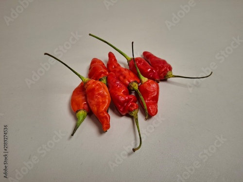 фотографія Fresh red and orange chili peppers with green stems arranged on a clean, neutral background with copy space