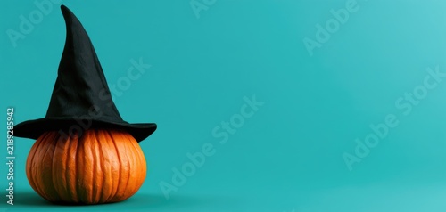 Orange pumpkin with witch hat on turquoise Halloween background