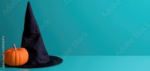 Orange pumpkin and witch hat on turquoise Halloween background