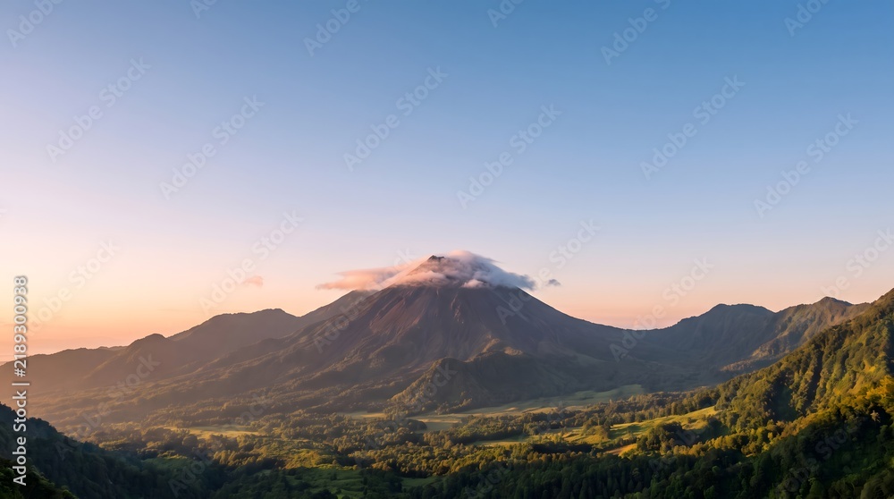 Obraz premium Mountain peak capped with a single cloud stands over a lush green valley at sunrise.