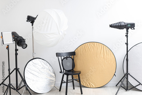 Different modern lighting equipment and chair in photo studio