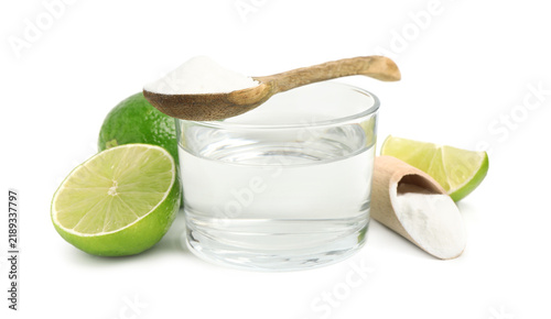 Foto Baking soda in wooden spoon, scoop, water and limes isolated on white
