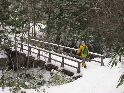 冬の乗鞍高原で凍った橋を渡る登山者