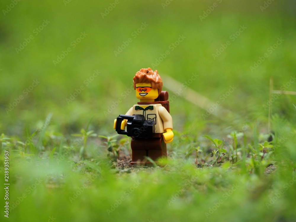 Obraz premium Indonesia - September 16, 2024 : Mini toy of action figure on hand at outdoor with blurred background. Miniature photography concept. Adventure man with backpack.
