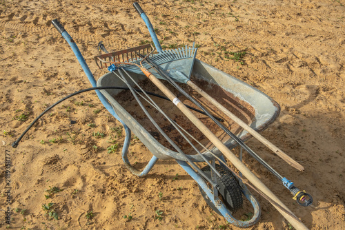 Fotografía Country background with wheelbarrow and garden tools.
