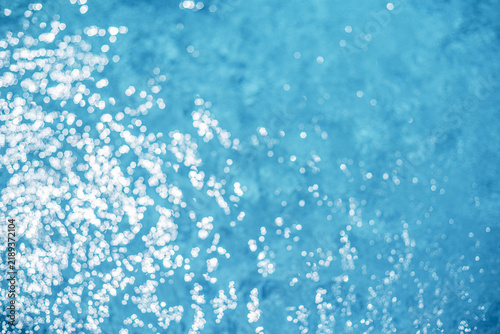 Fotografie Sunlit rippled blue water texture background in swimming pool.