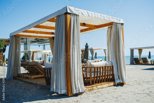 Foto Beach cabana with lounge beds under clear blue sky at a seaside resort during th