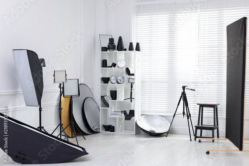 Different modern lighting equipment and tripod in photo studio