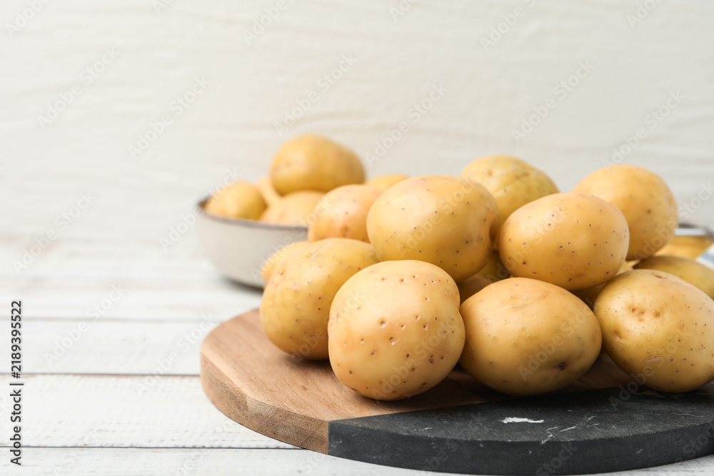 Fototapeta premium Ripe raw young potatoes on white wooden table, closeup. Space for text