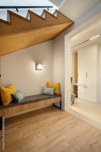Quadro su tela A modern minimalist entryway featuring a wooden bench with soft cushions beneath