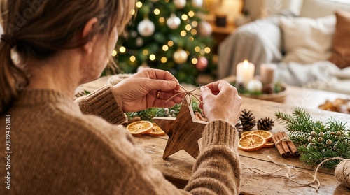 Woman making Christmas decoration tying twine wooden star holiday crafting