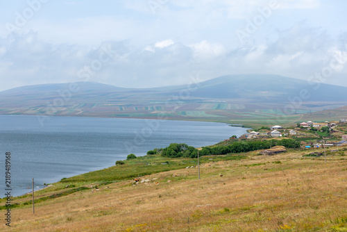 Lake Paravani with hills and green vegetation under a foggy sky, Javakheti