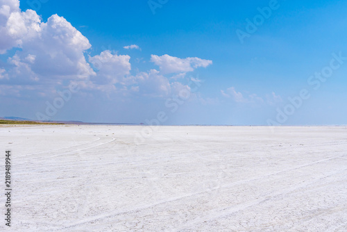 Vast white salt flat under a clear blue sky with scattered clouds. Turkey