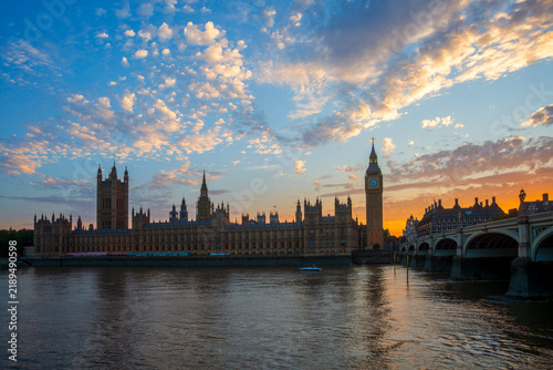 Sunset glow scenery of Big Ben and the Houses of Parliament along the Thames River in London, England.