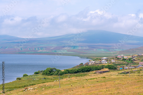 Lake Paravani with hills and green vegetation under a foggy sky, Javakheti
