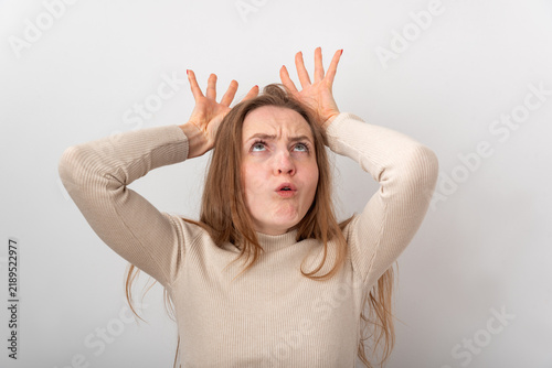 Принти на полотні Young woman looking up with a humorous facial expression, holding hands to her h