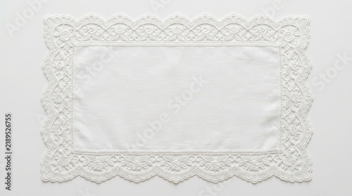 Elegant white lace placemat with intricate floral embroidery and scalloped edges perfect for vintage table settings or decorative wedding linens on surface.