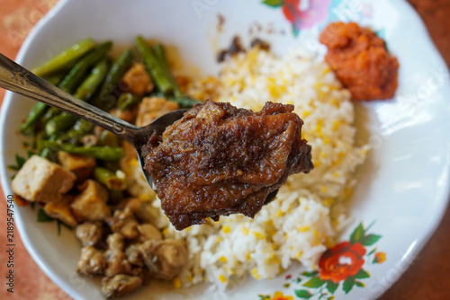 Bild auf Leinwand Indonesian corn rice served with soy glazed chicken, stir-fried long beans, sambal, and savory side dishes on a floral ceramic plate, showcasing homestyle dining