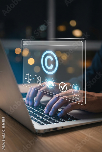 Close up of person typing on laptop with copyright icon and legal symbols interface