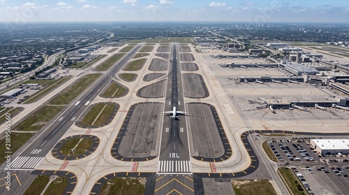 Aerial airport runway view, commercial airplane landing on tarmac, international aviation hub with terminal buildings and taxiways
