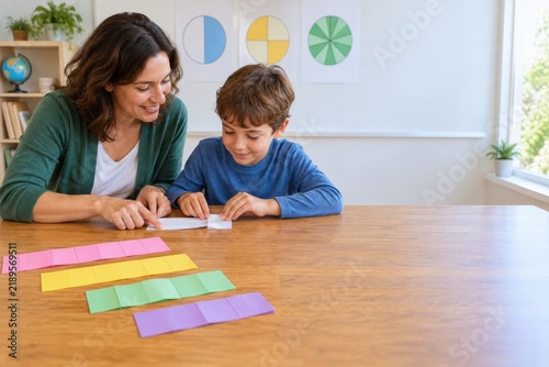 Teacher helping a boy learn fractions with paper strips