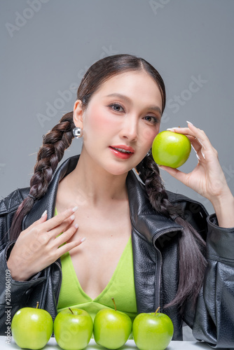 фотографія Trendy stylish woman balancing green apple on head, showcasing playful attitude, fashion beauty, quirky balance, youthful confidence, creative diet concept, modern wellness, and edgy cool lifestyle
