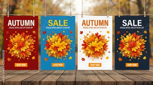 Four hanging vertical autumn sale posters in different colors with fall leaf arrangements, displayed on a wooden surface with a blurred forest background