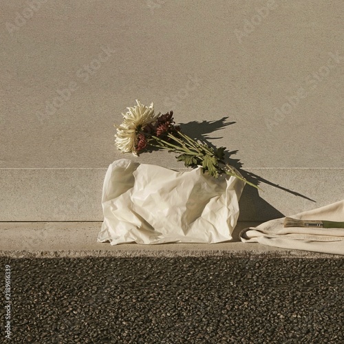 Granite chrysanthemum sculpture resting on a cemetery kerb with real flowers, featuring a honed stone texture for memorial masonry advertising
