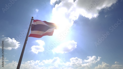 Thailand Flag waving on a Flagpole from a Moving Angle in front of a blue sky with clouds	
