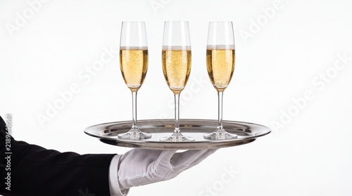 Waiter hand holding shiny metal tray with three sparkling champagne glasses captured on white background