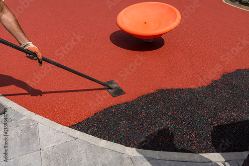 smoothing shiny reddish brown surface with trowel, making future playground