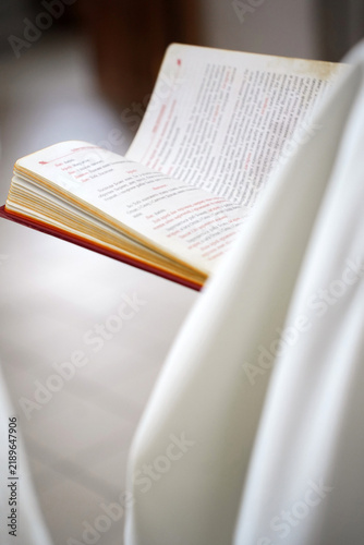 Fotografie An open liturgical book with printed text rests among white fabrics during a church wedding ceremony and worship
